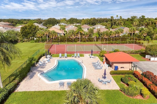 view of pool with a lawn and tennis court