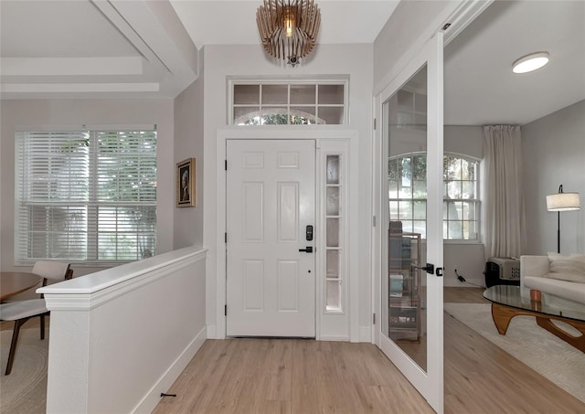 entrance foyer with light wood-type flooring, plenty of natural light, and a notable chandelier