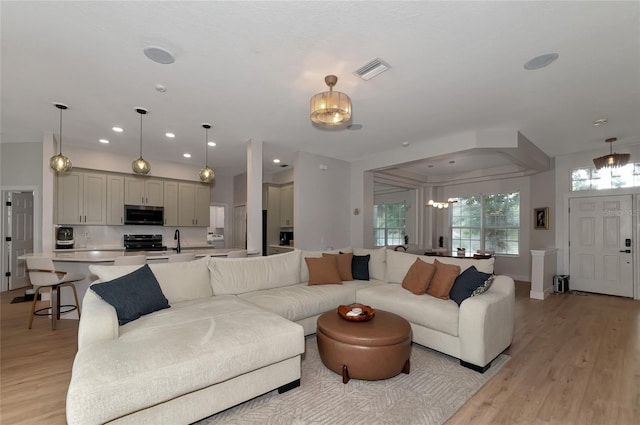 living room featuring a notable chandelier, sink, and light hardwood / wood-style floors