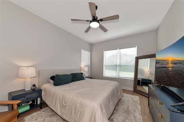 bedroom with ceiling fan, light wood-type flooring, and vaulted ceiling