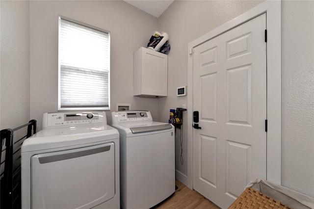 laundry room featuring a wealth of natural light, cabinets, washing machine and dryer, and light hardwood / wood-style floors