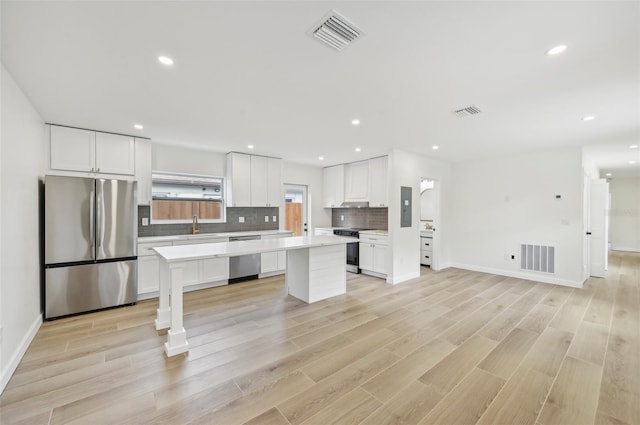 kitchen with white cabinets, light hardwood / wood-style floors, and stainless steel appliances