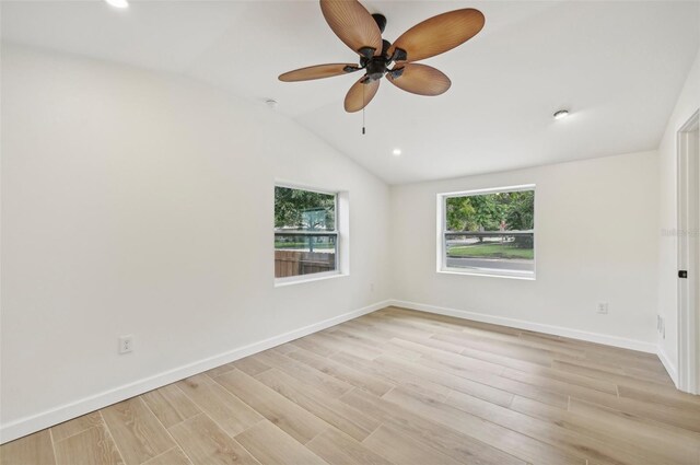 empty room with ceiling fan, light hardwood / wood-style floors, and vaulted ceiling