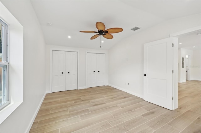 unfurnished bedroom featuring two closets, light hardwood / wood-style floors, ceiling fan, and lofted ceiling