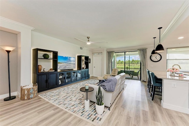 living room featuring ceiling fan, crown molding, and light hardwood / wood-style floors