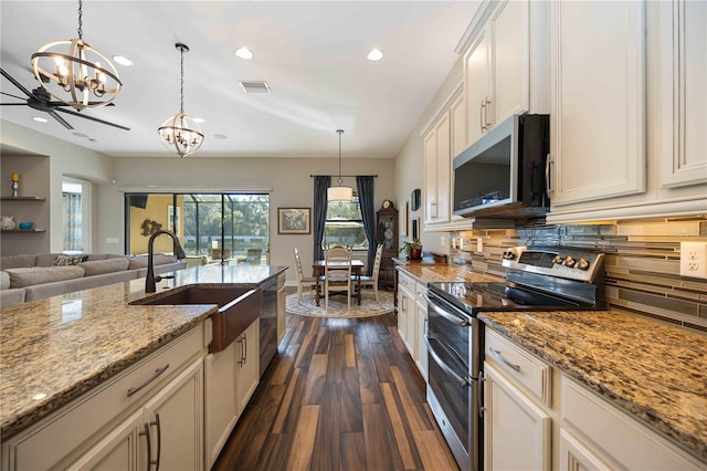 kitchen with ceiling fan with notable chandelier, decorative light fixtures, stainless steel appliances, dark hardwood / wood-style flooring, and sink