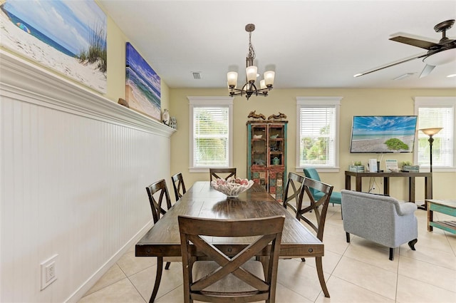 tiled dining space with ceiling fan with notable chandelier and a healthy amount of sunlight