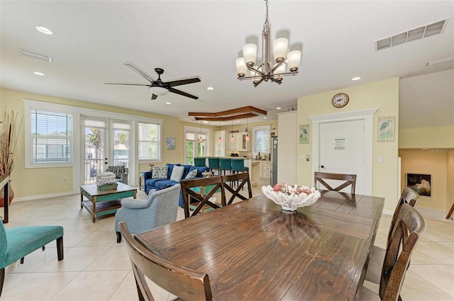 tiled dining area featuring ceiling fan with notable chandelier