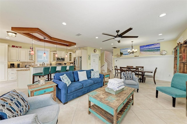 tiled living room featuring ceiling fan with notable chandelier and sink