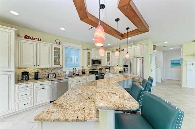 kitchen with pendant lighting, a kitchen breakfast bar, sink, appliances with stainless steel finishes, and a large island