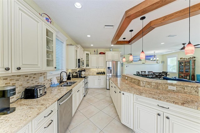 kitchen featuring pendant lighting, stainless steel appliances, light stone countertops, and sink