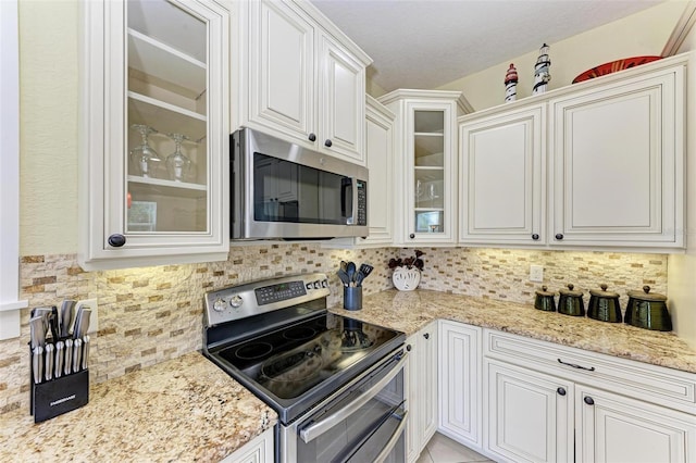 kitchen with backsplash, appliances with stainless steel finishes, and white cabinets