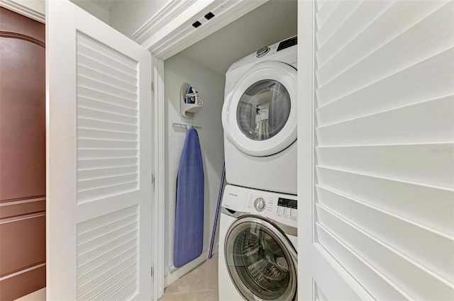 clothes washing area featuring light tile patterned flooring and stacked washing maching and dryer