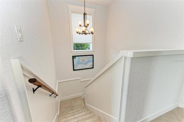 staircase featuring an inviting chandelier and tile patterned floors