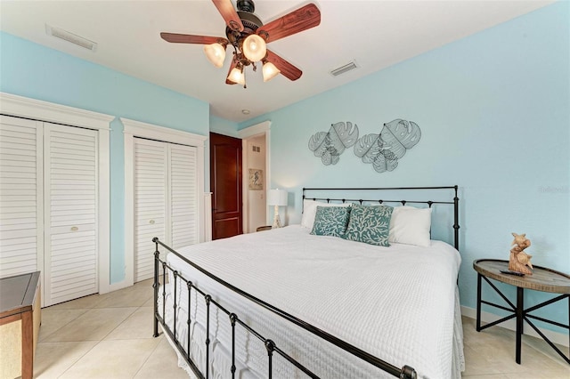 tiled bedroom featuring ceiling fan and two closets