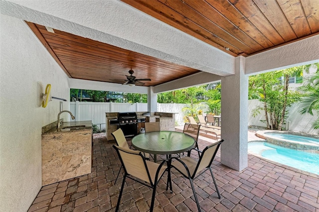 view of patio / terrace featuring an in ground hot tub, exterior kitchen, sink, ceiling fan, and area for grilling