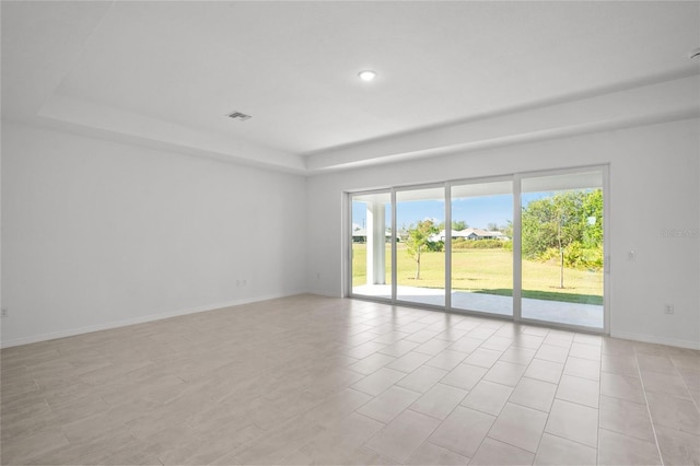 tiled spare room with a tray ceiling