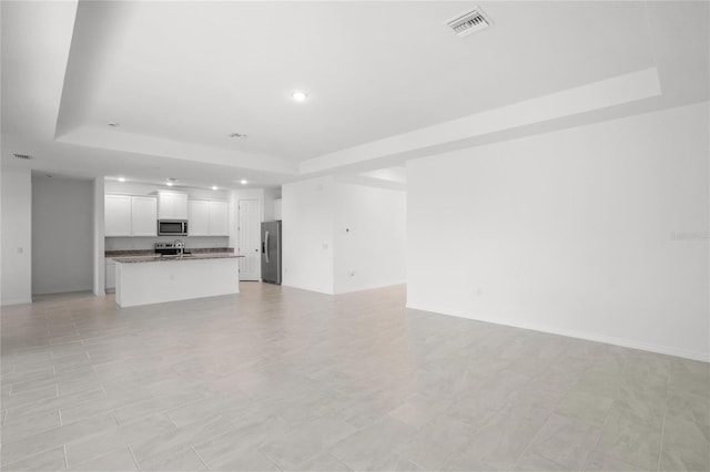 unfurnished living room featuring a tray ceiling