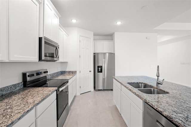 kitchen with light stone counters, white cabinetry, sink, and appliances with stainless steel finishes