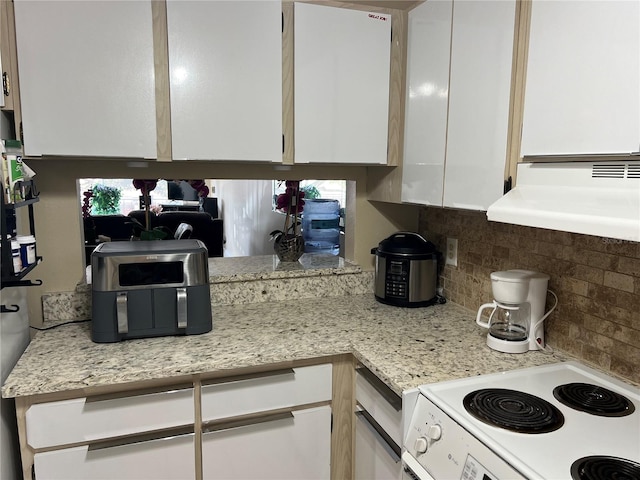 kitchen featuring range, backsplash, white cabinetry, and light stone counters