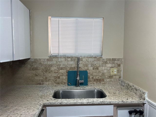 kitchen featuring backsplash, light stone counters, and sink