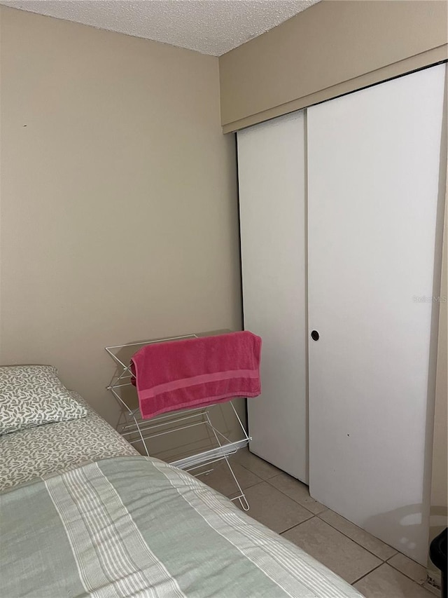 bedroom with a closet, a textured ceiling, and tile patterned flooring