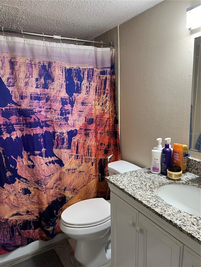 bathroom with vanity, a textured ceiling, toilet, and curtained shower