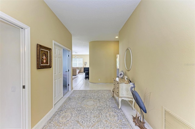 corridor featuring light tile patterned flooring and a textured ceiling