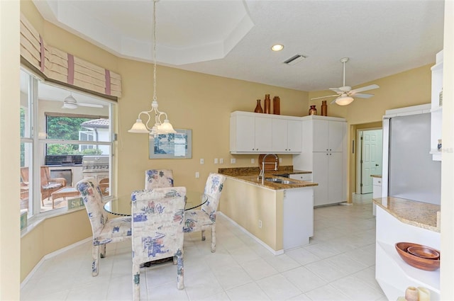 kitchen featuring ceiling fan with notable chandelier, sink, decorative light fixtures, white cabinets, and light tile patterned flooring