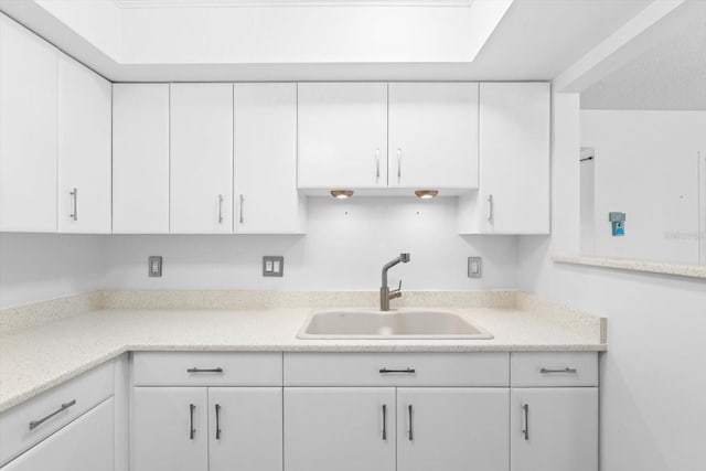 kitchen with light countertops, a sink, and white cabinetry