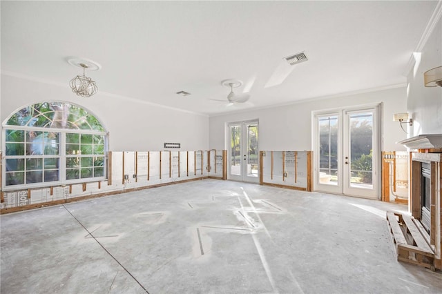 unfurnished living room with ceiling fan with notable chandelier, crown molding, and french doors