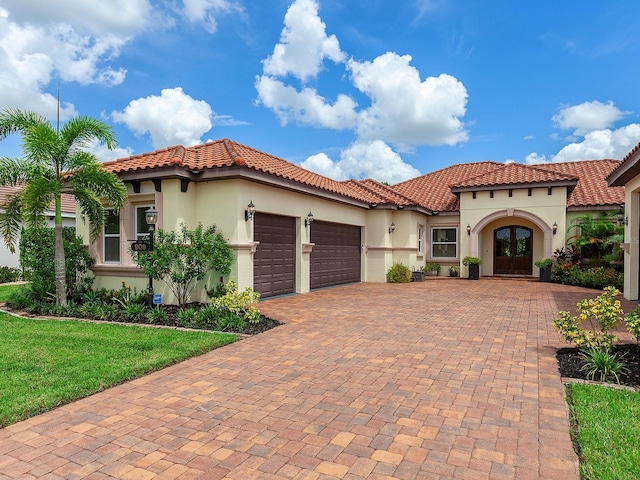 mediterranean / spanish house with a garage and a front lawn