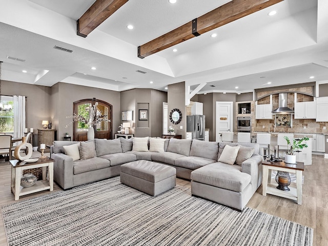 living room with light wood-type flooring, beamed ceiling, and plenty of natural light