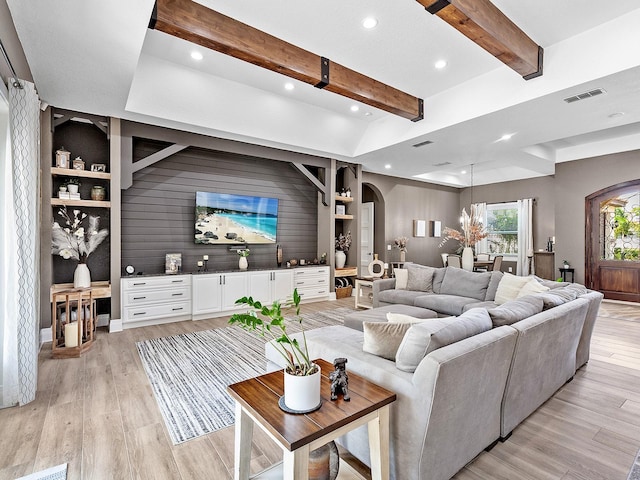 living room featuring light wood-type flooring and vaulted ceiling with beams