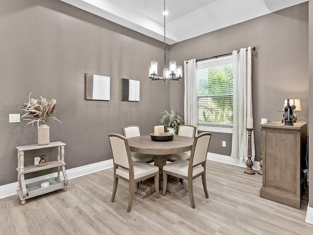 dining room featuring lofted ceiling, light wood-type flooring, and a chandelier