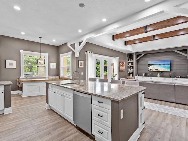 kitchen with stainless steel dishwasher, plenty of natural light, a center island with sink, and sink