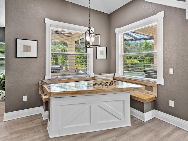 dining room with ceiling fan with notable chandelier, plenty of natural light, and light hardwood / wood-style floors