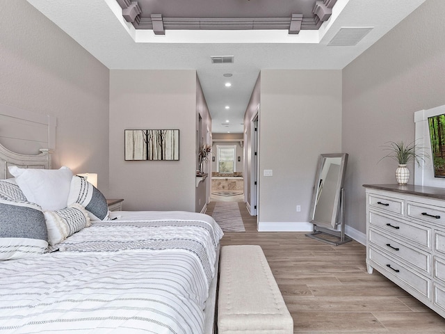 bedroom with ensuite bath and light wood-type flooring