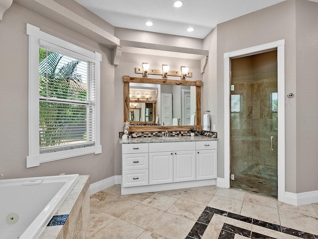 bathroom featuring independent shower and bath, a wealth of natural light, and vanity