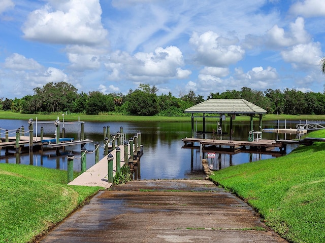 view of dock with a lawn and a water view