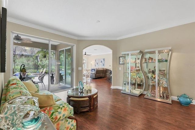 living room with a wealth of natural light, dark wood-type flooring, ceiling fan, and ornamental molding