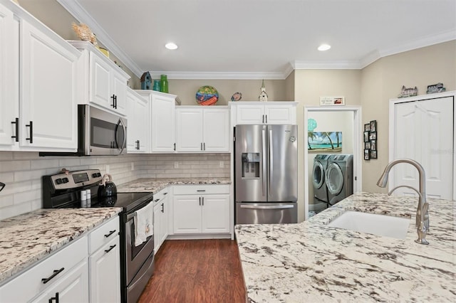 kitchen with white cabinetry, washing machine and dryer, stainless steel appliances, and sink