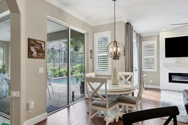 dining room featuring ornamental molding, a chandelier, hardwood / wood-style floors, and a large fireplace