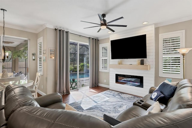 living room with crown molding, hardwood / wood-style floors, ceiling fan, and a large fireplace