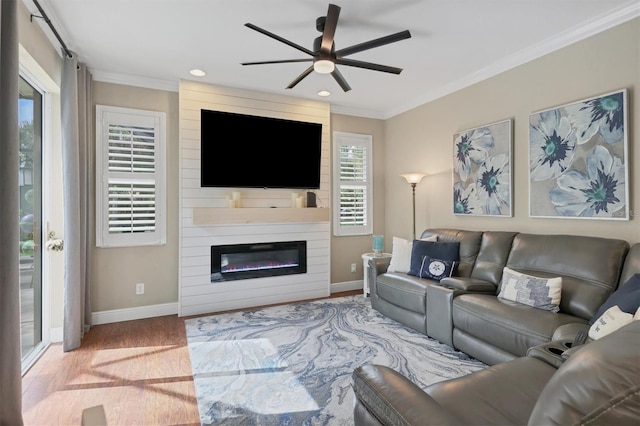 living room featuring a fireplace, crown molding, light hardwood / wood-style flooring, and ceiling fan