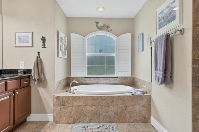 bathroom with tile patterned flooring, tiled tub, and vanity