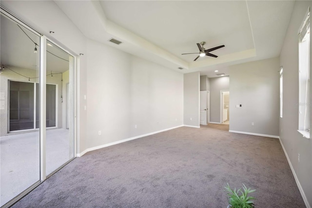 spare room featuring ceiling fan, a raised ceiling, and carpet floors