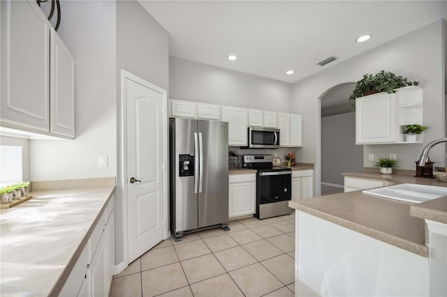 kitchen with white cabinetry, appliances with stainless steel finishes, light tile patterned flooring, and sink