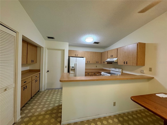 kitchen featuring a textured ceiling, lofted ceiling, kitchen peninsula, and white appliances