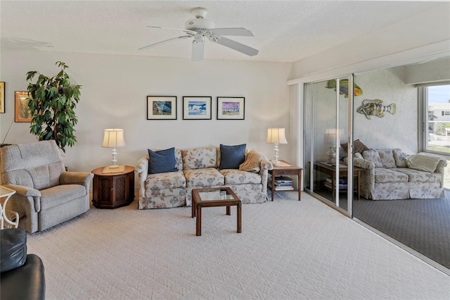 carpeted living room featuring ceiling fan and a textured ceiling